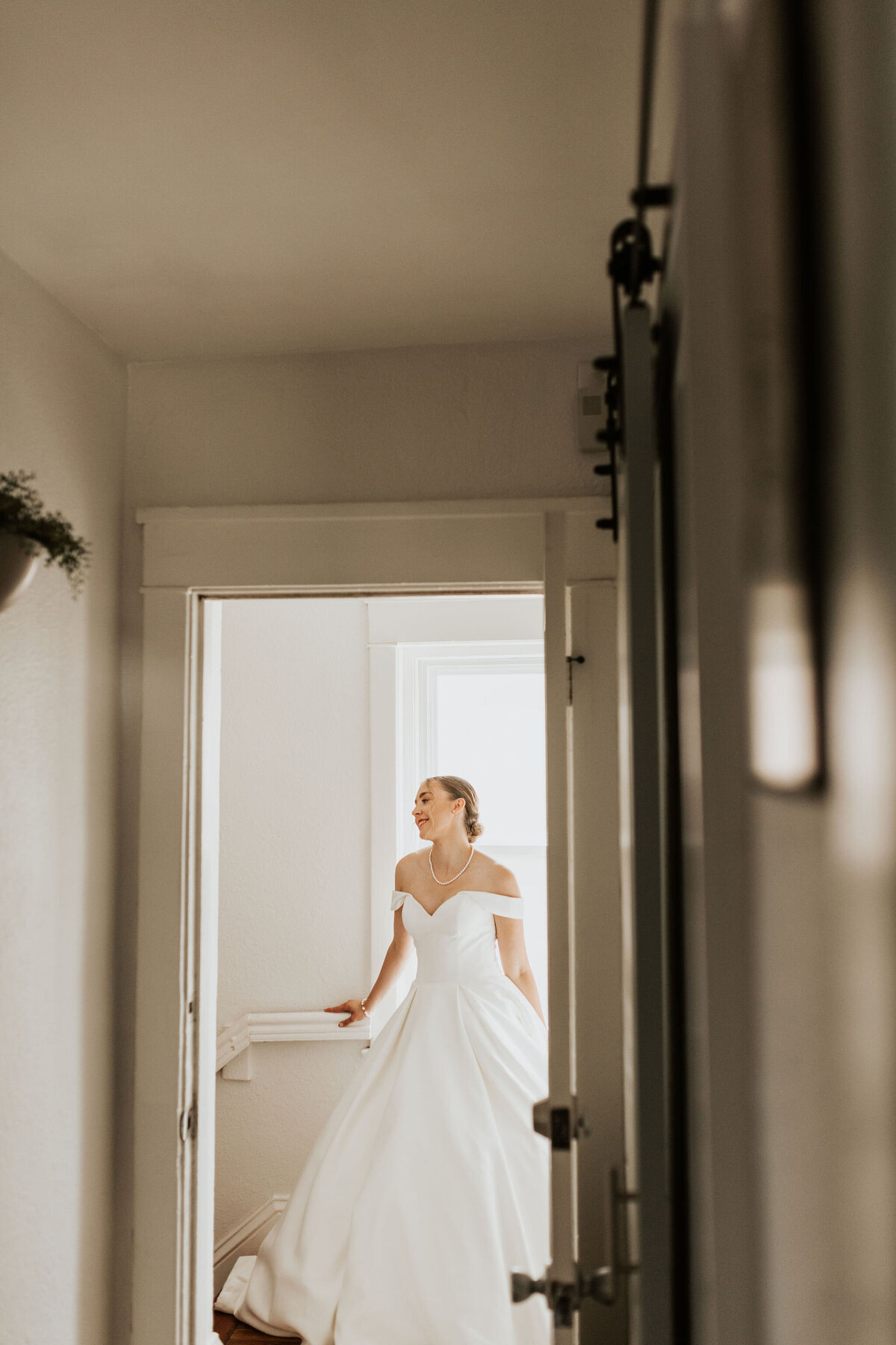 a bride in a sunlit room near a shadowy hallway