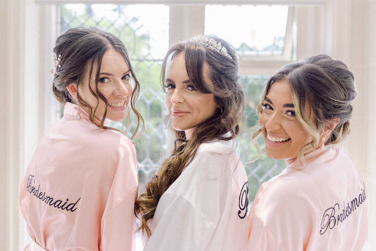 Bride and bridesmaids looking over their shoulder at the camera wearing bridal party robes