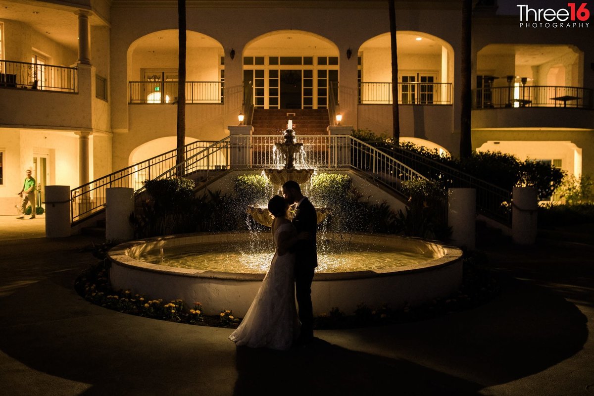 Silhouette of Bride and Groom kissing in front of the water fountain at night