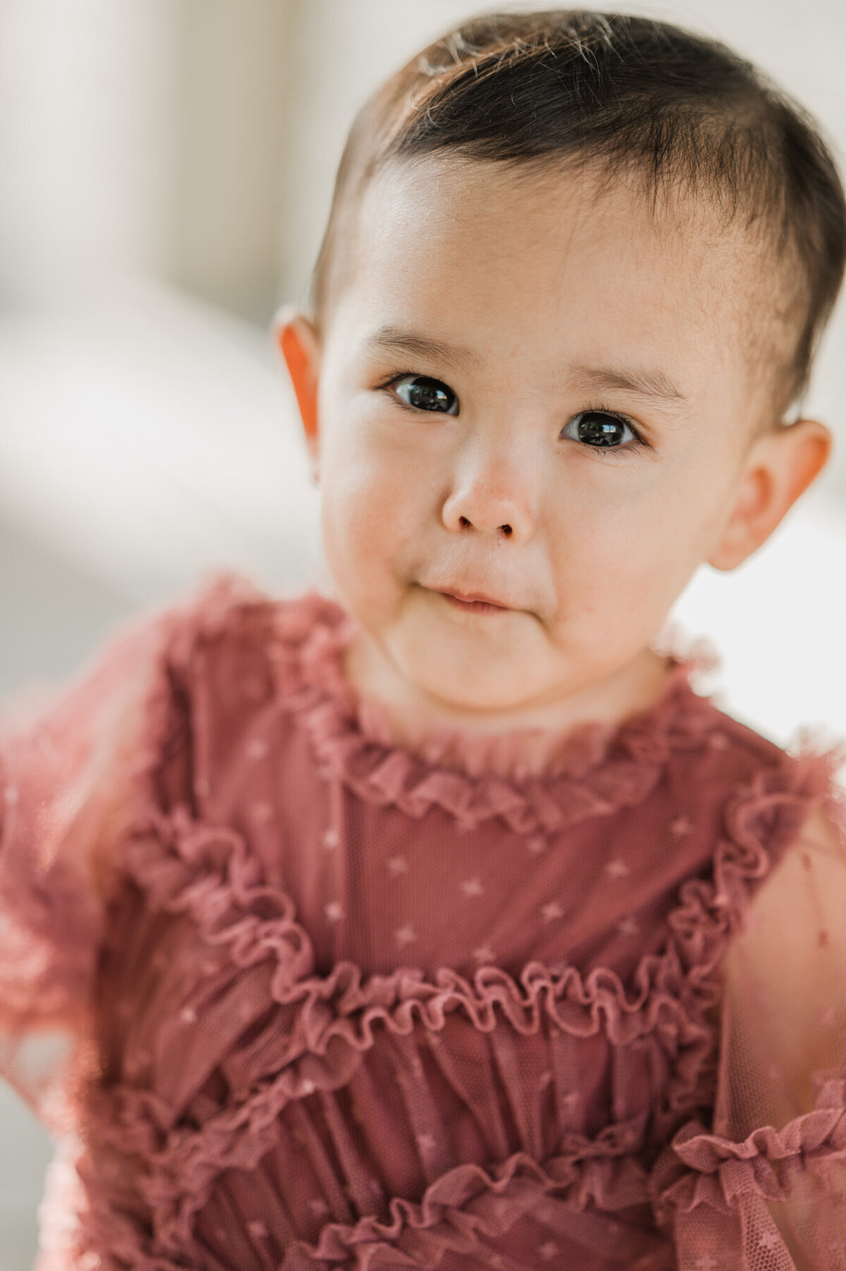 Close-up portrait of a little girl in a pink dress.