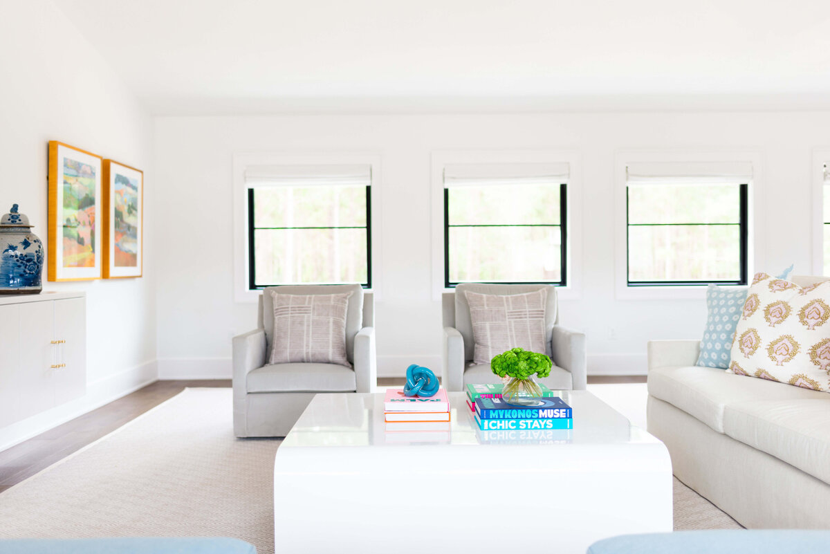 oyster creek studios building belt new build two gray armchairs and gray sofa with white coffee table in living room near windows
