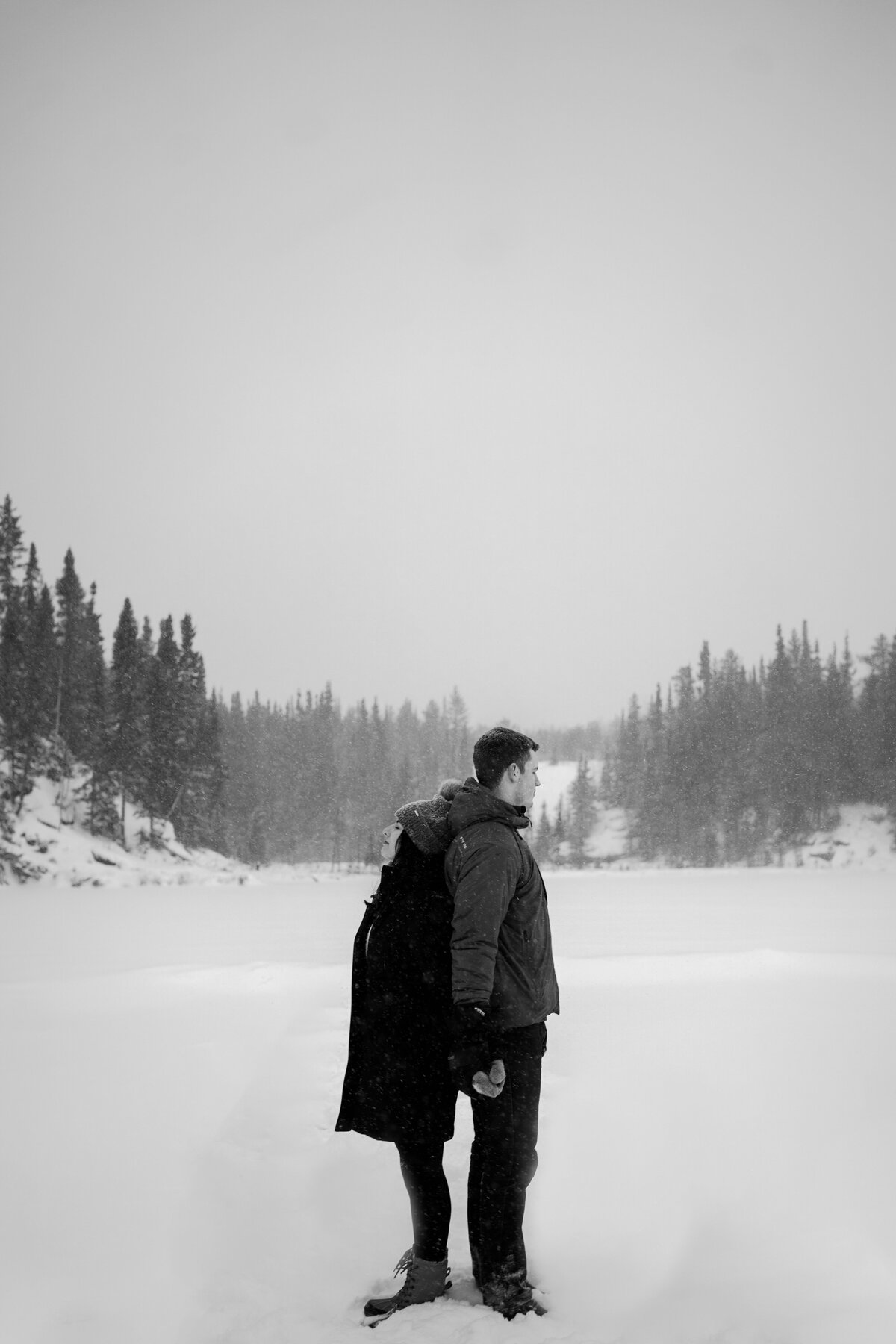 black and white image couple back to back in snow