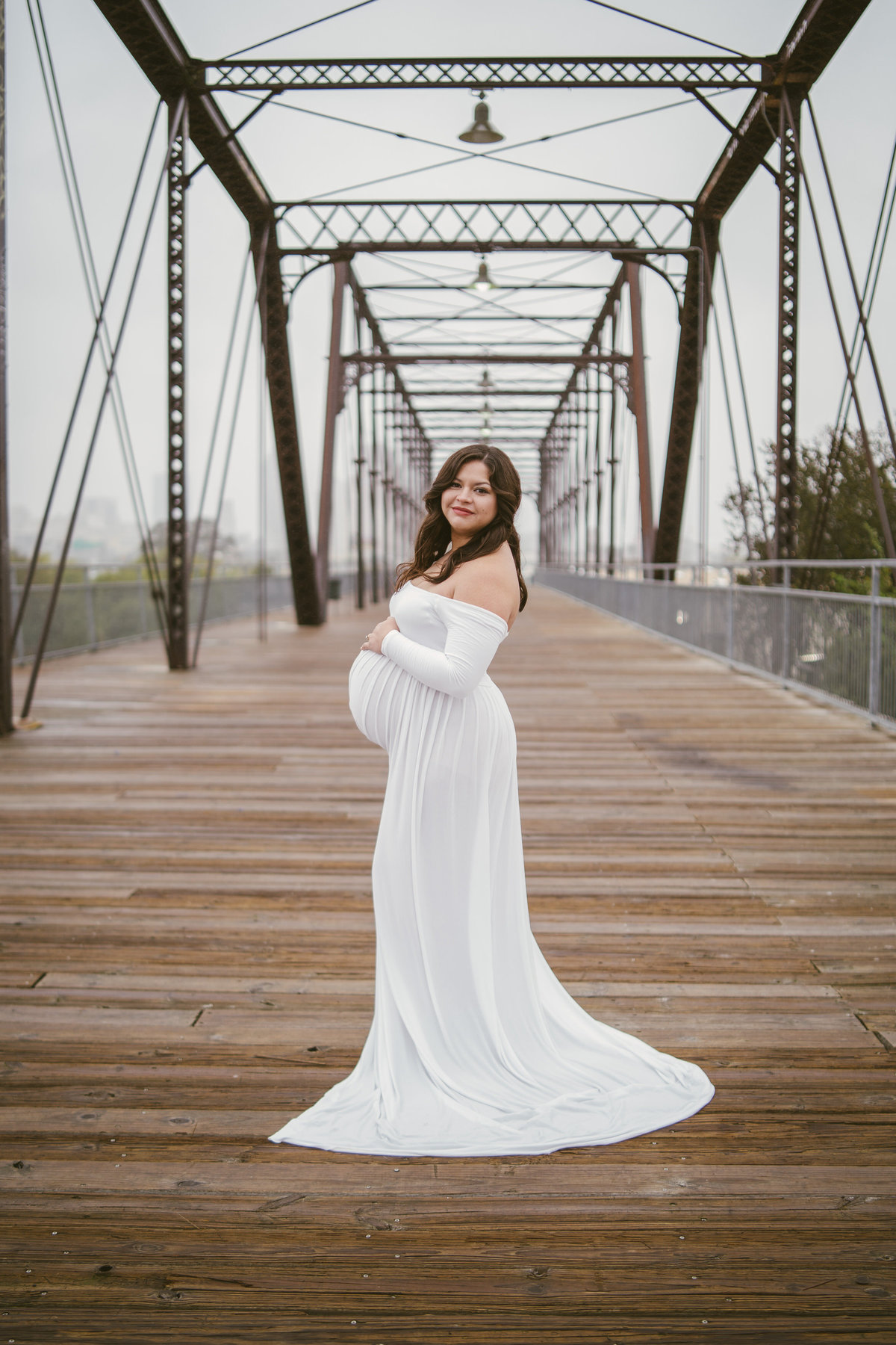 Woman in white maternity dress posing on the Hays Street Bridge in San Antonio.