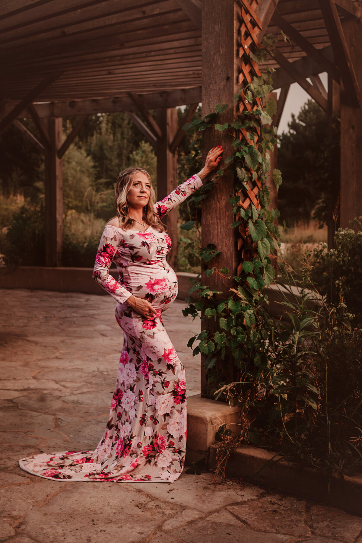 Mother holding belly while wearing long floral dress