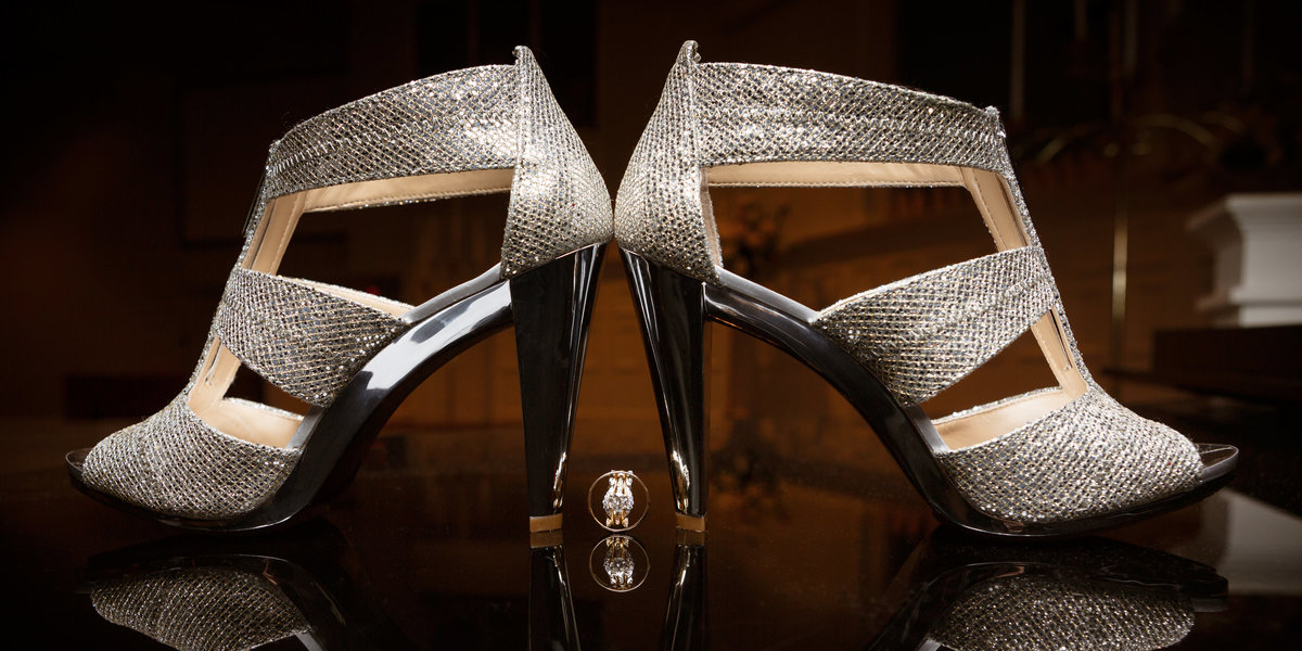 Detail shot of wedding rings and brides high heel shoes.