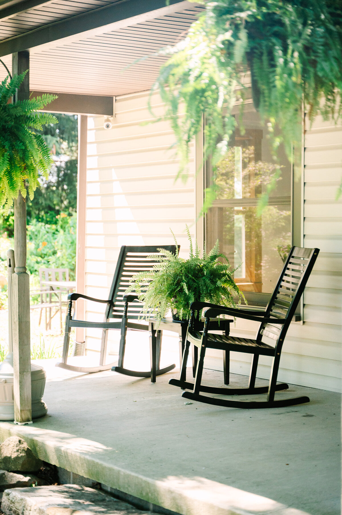 black rocking chairs and lush ferns on the front porch of the overnight accommodations Modern Farmhouse at Willowbrook wedding venue