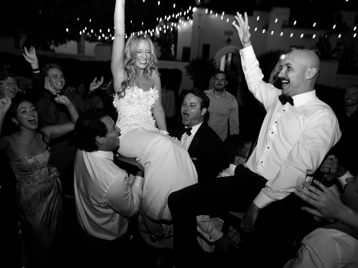 Bride and groom being lifted up at wedding reception