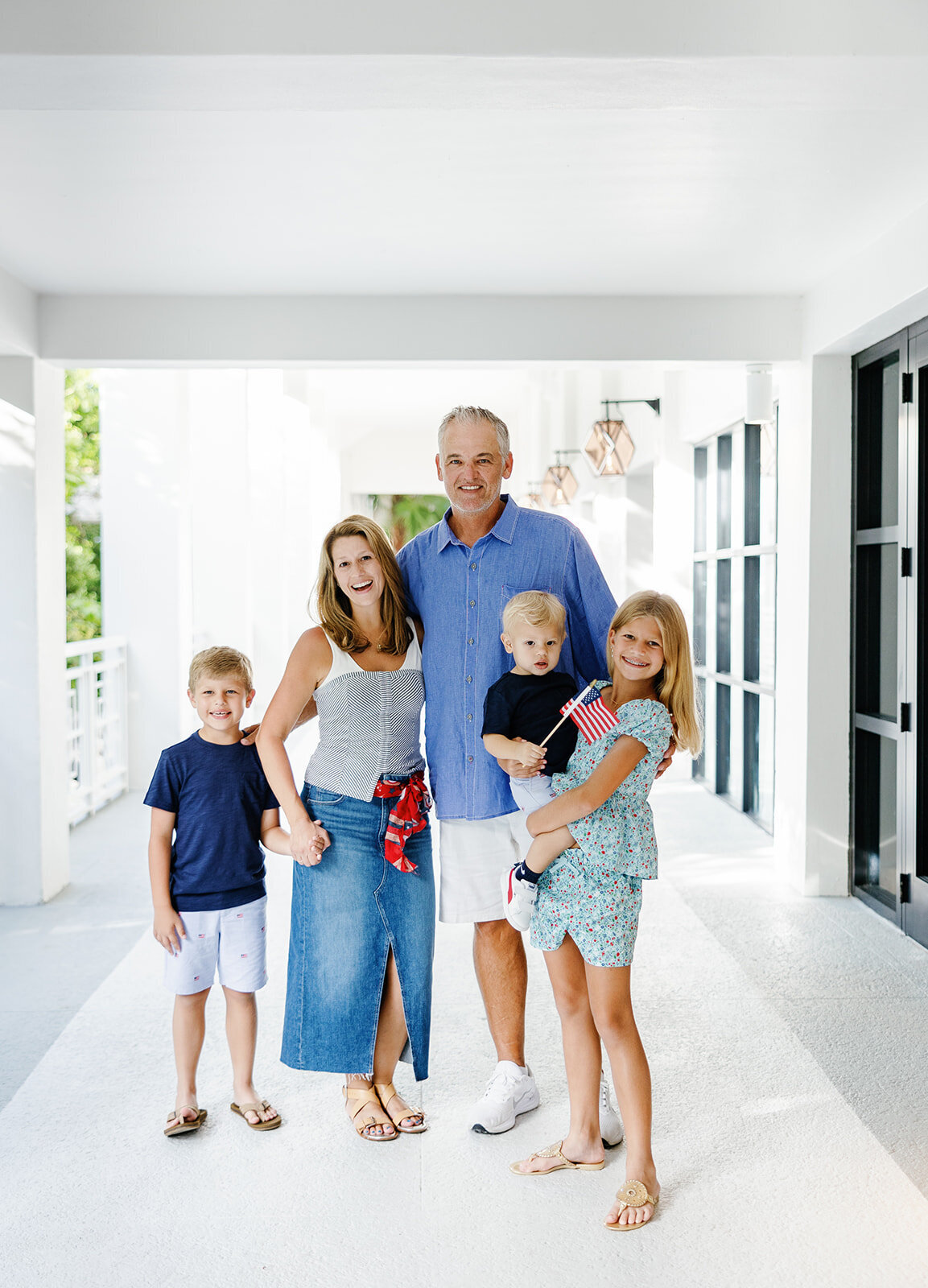 A happy family stands together in a bright white hallway, radiating warmth and joy during a Florida Keys family photography session.