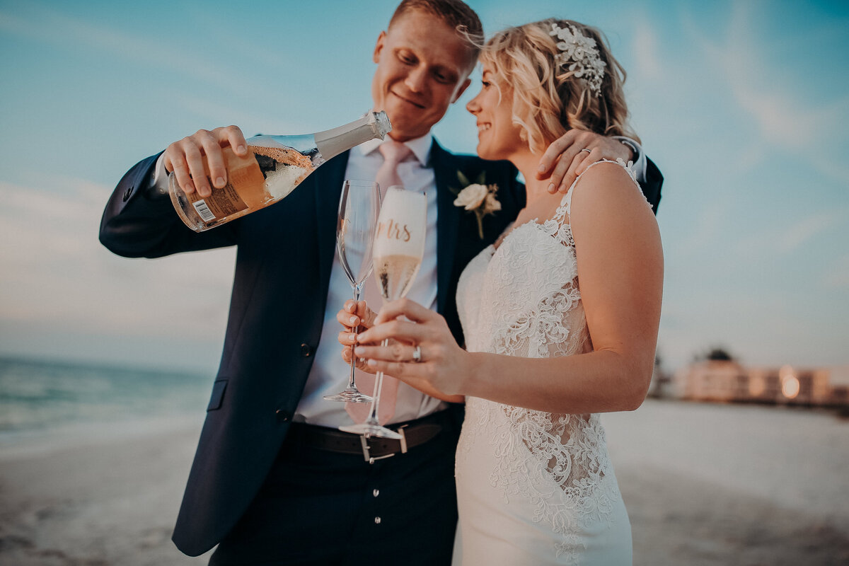A wedding couple celebrates with champagne on the beach during sunset in Sarasota, Florida- photo by The Astralis Collective, a photo + film team. 