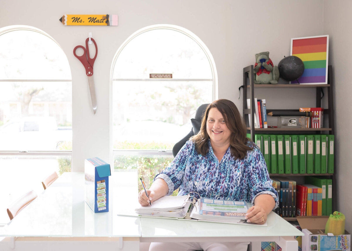 Tutor for small kids in her light and bright, nicely decorated office sitting at her desk smiling