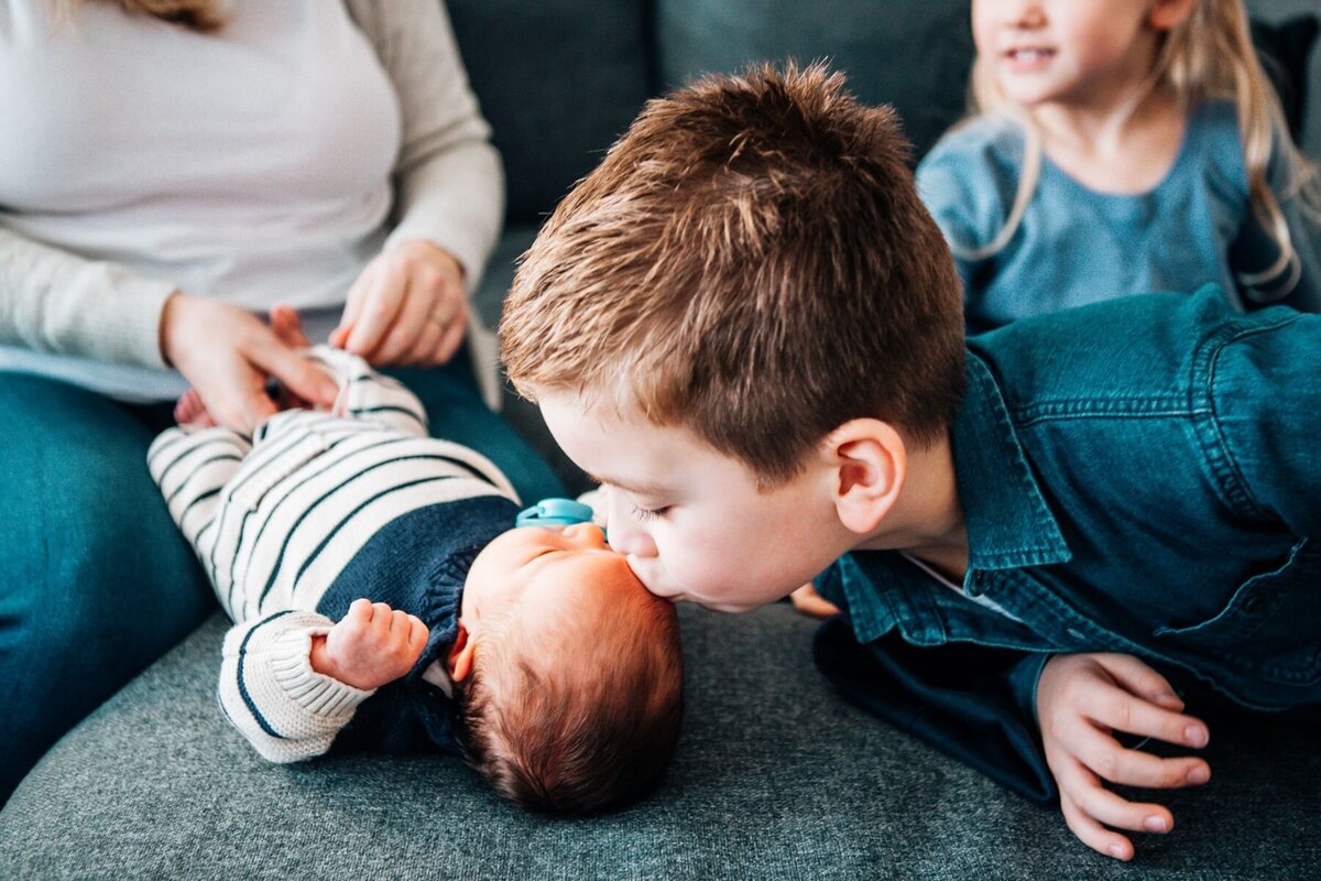 Big brother kisses new baby brother during their photoshoot.