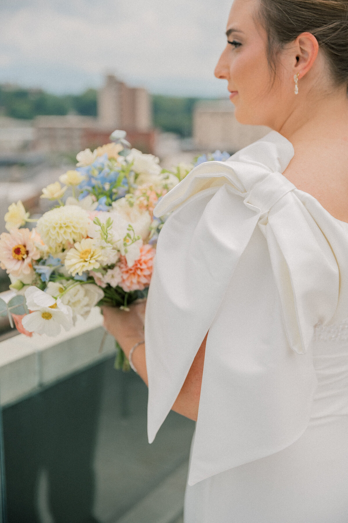 Bride with bow sleeve and colorful bridal bouquet on the rooftop of the Bristol Hotel before her Bristol Train Station wedding
