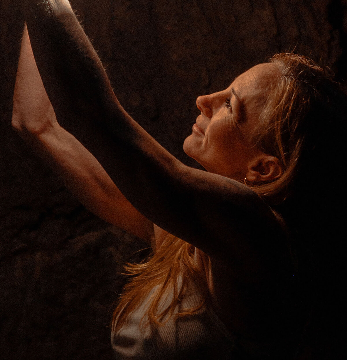 woman looks up at the golden light while standing in Bend, Oregon cave