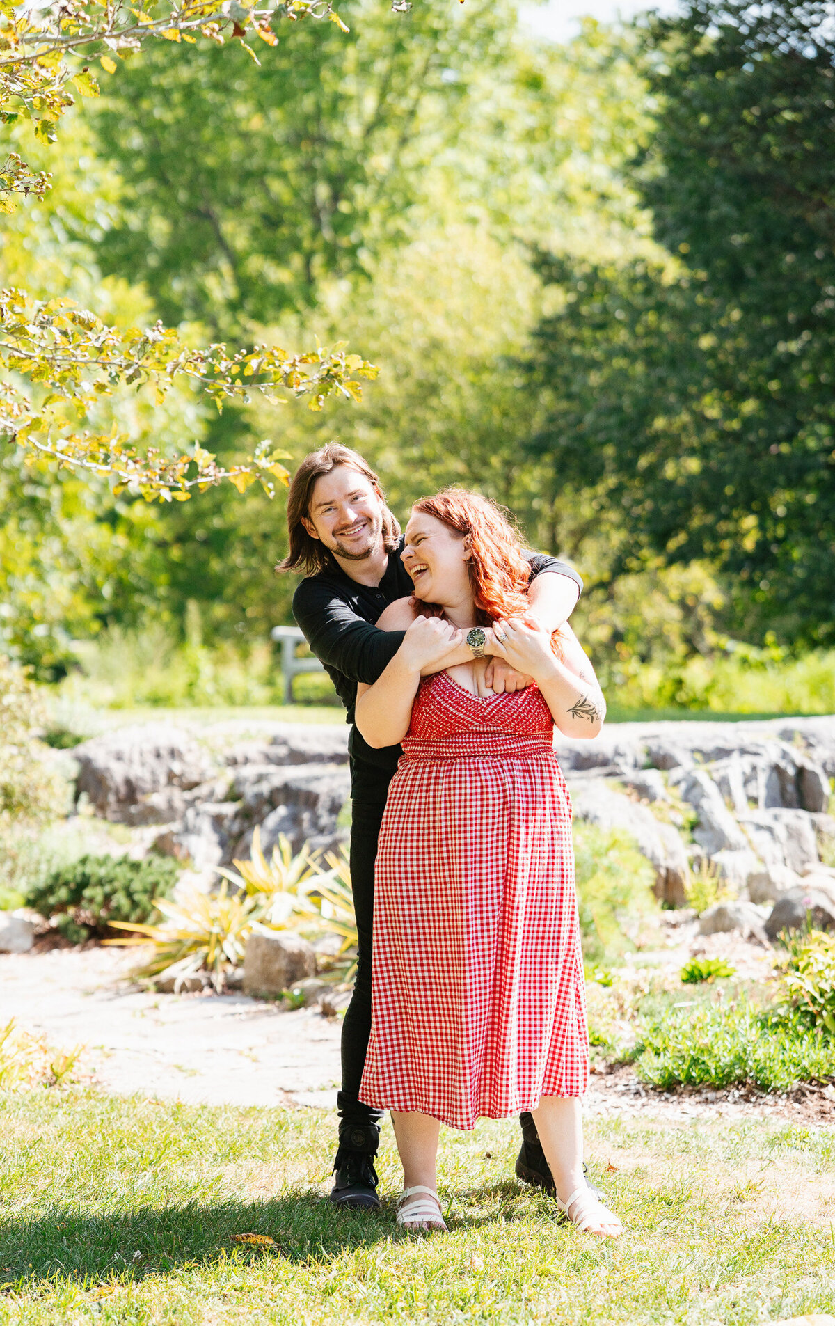 Candid engagement portraits at Acton Arboretum in Massachusetts with greenery and emotion.