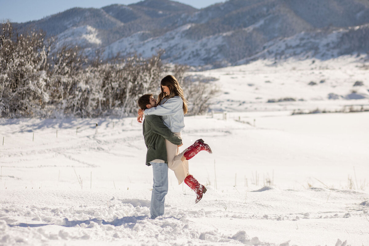 man picking up woman in snowy mountain location