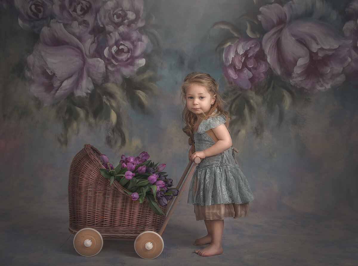 Girl in dainty dress pusing stroller with flowers taken in indoor portrait studio in Ottawa Ontario