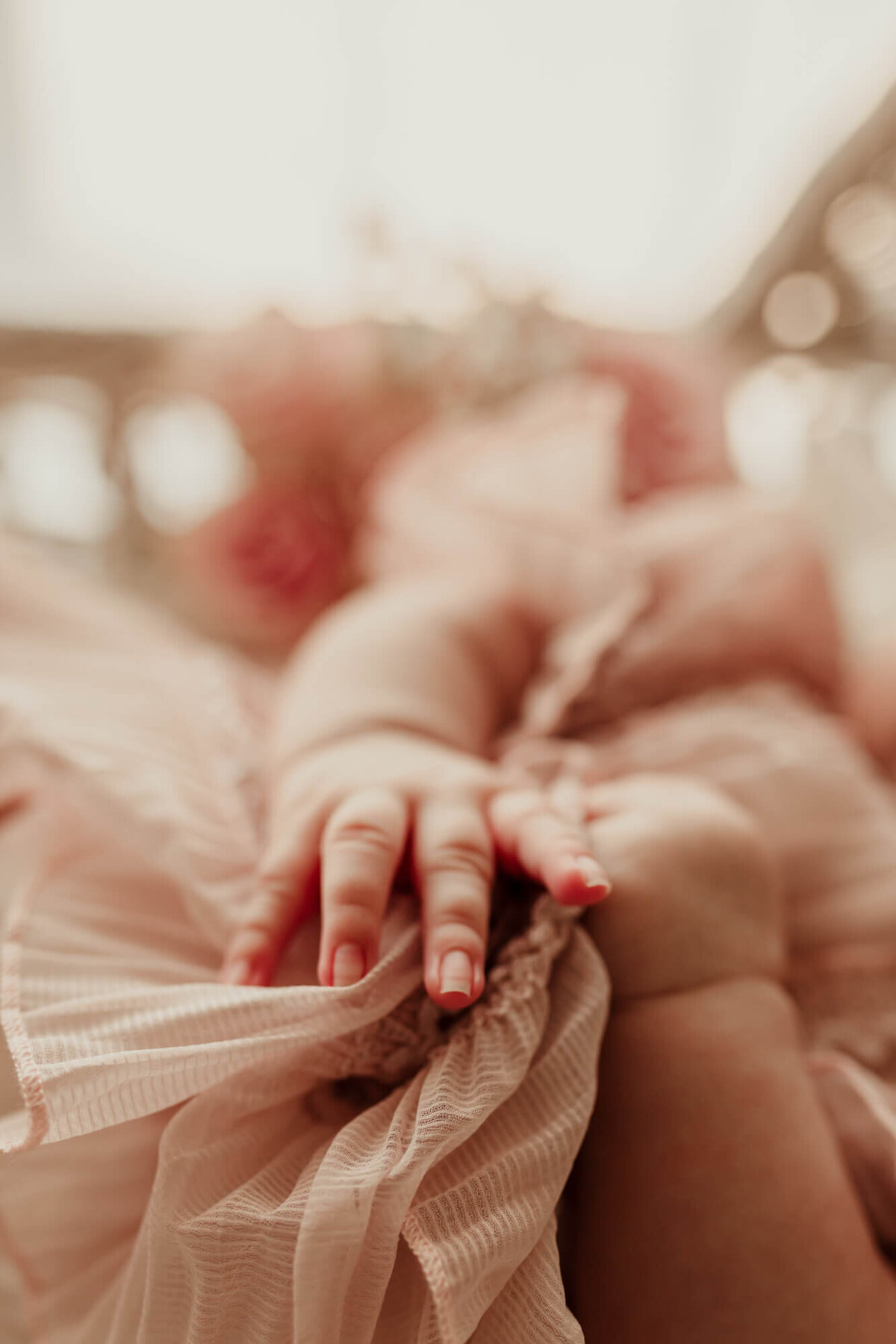 Close up of a baby girl's hands holding her pink dress.