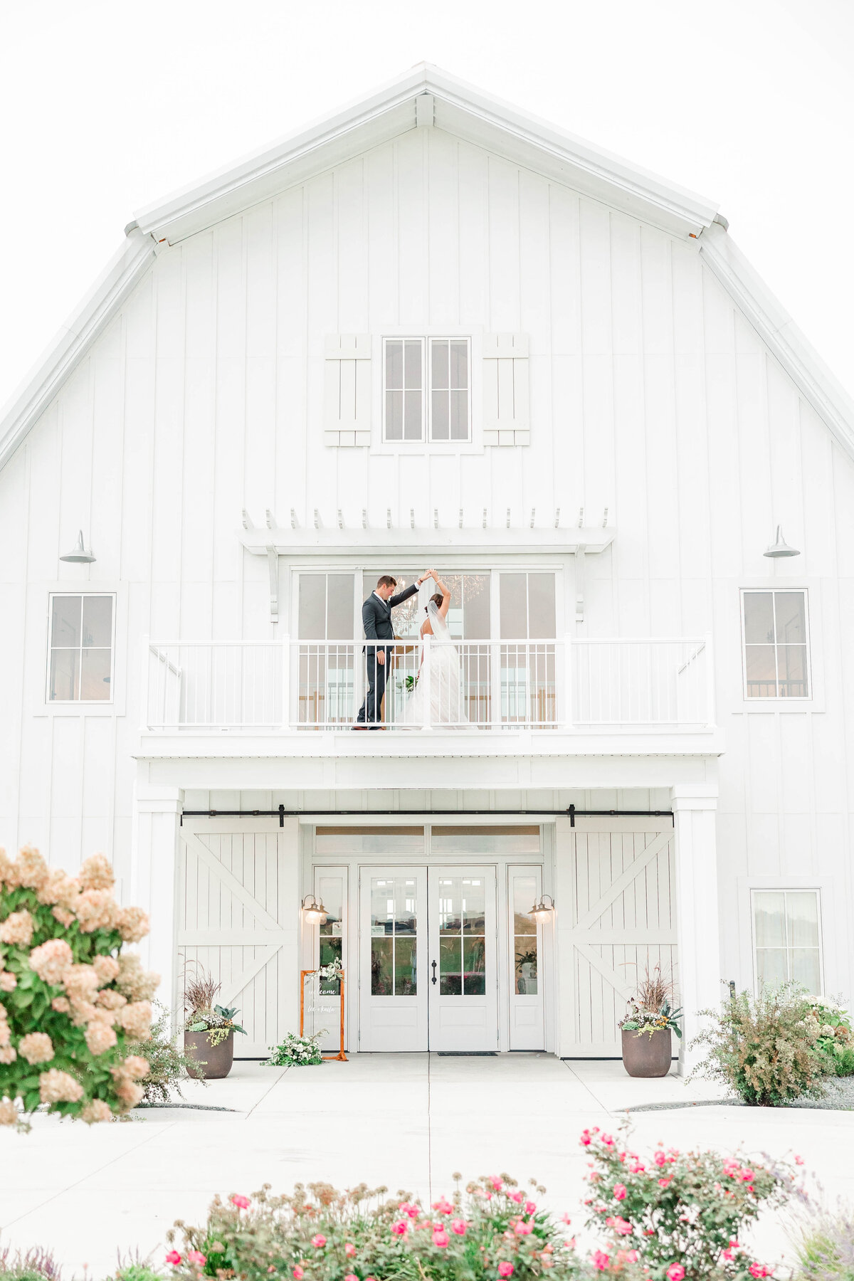 Bride and groom spin on white barn balcony