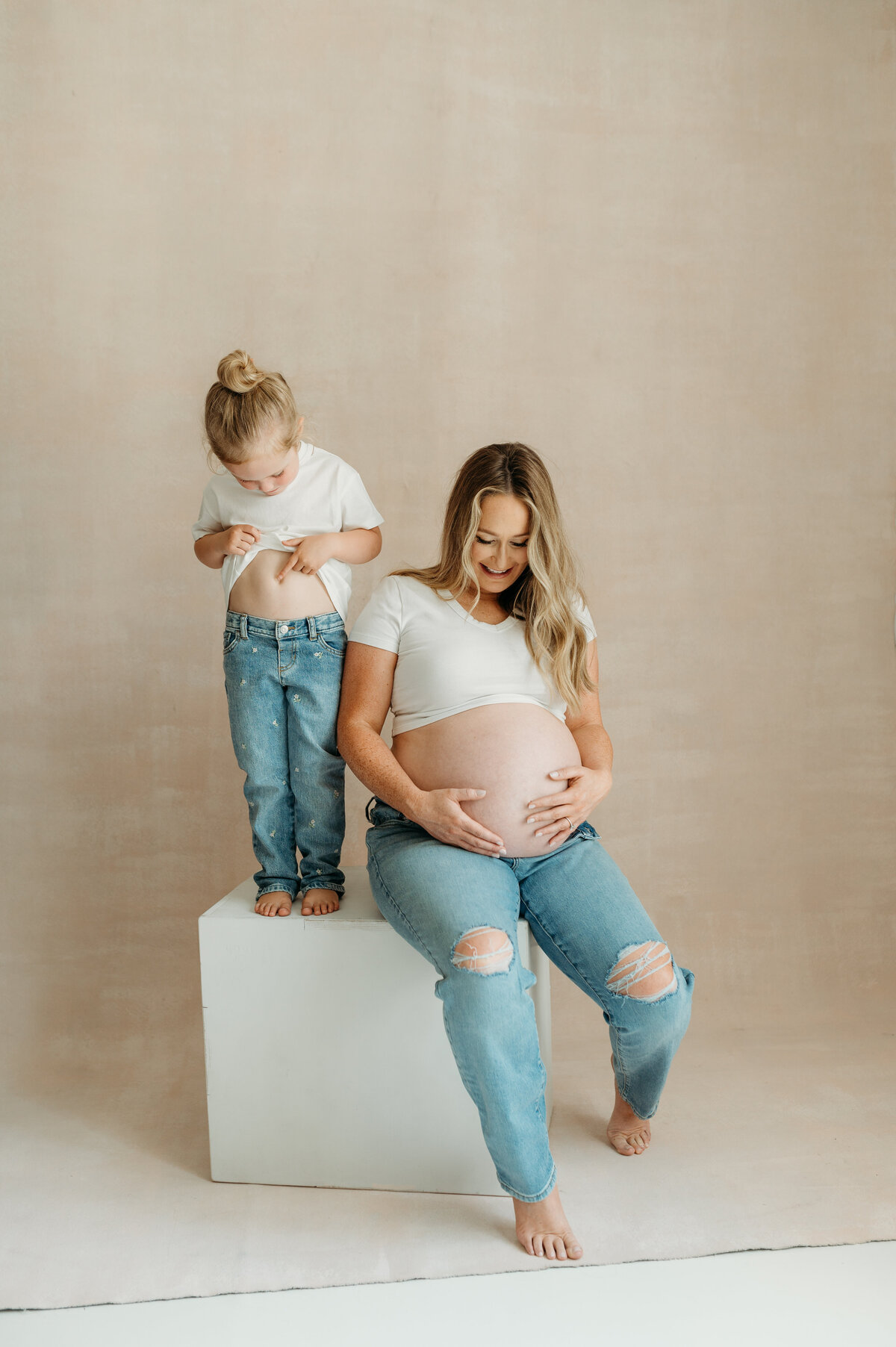 Mom and daughter looking at their bellies