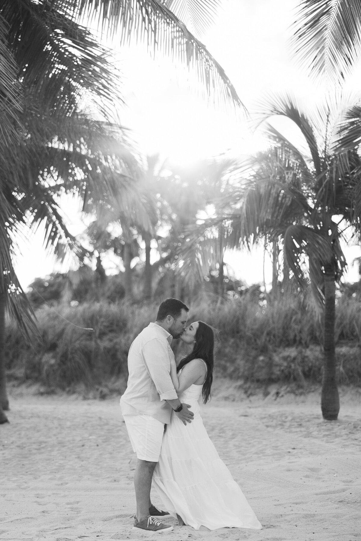 Romantic engagement photo of a couple kissing on the beach in Miami, captured by Claudia Amalia, a wedding and lifestyle photographer based in Miami and Florida Keys, South Florida. Specializing in destination weddings.