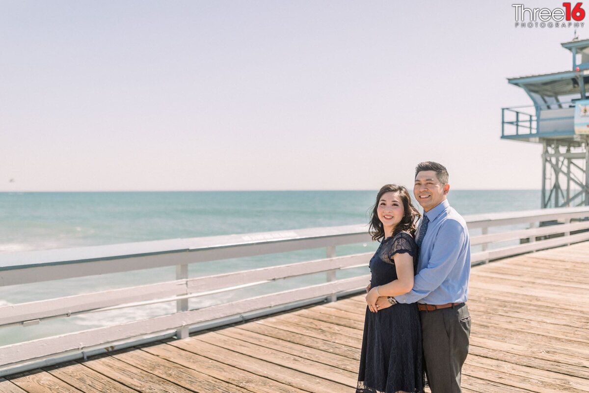 Bride to be cozies up to her fiance for photo shoot on the San Clemente Pier