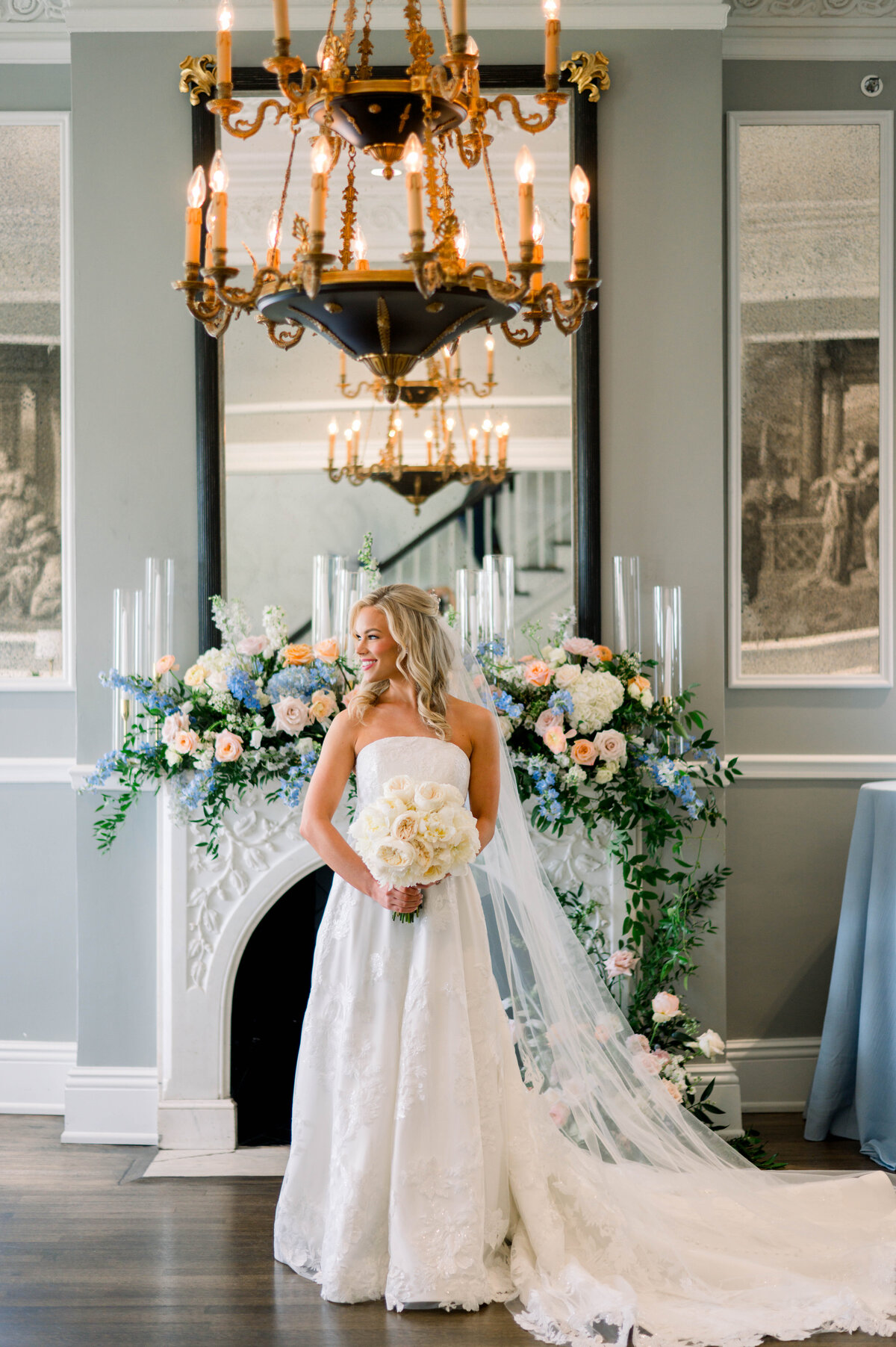Bride posed in front of decorated fireplace with colorful summer florals at University Club wedding
