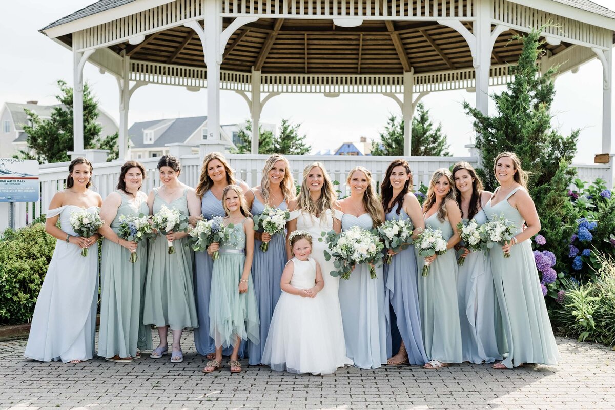 Bride and bridesmaids photographed by the gazebo in Belmar NJ wearing shades of green and blue