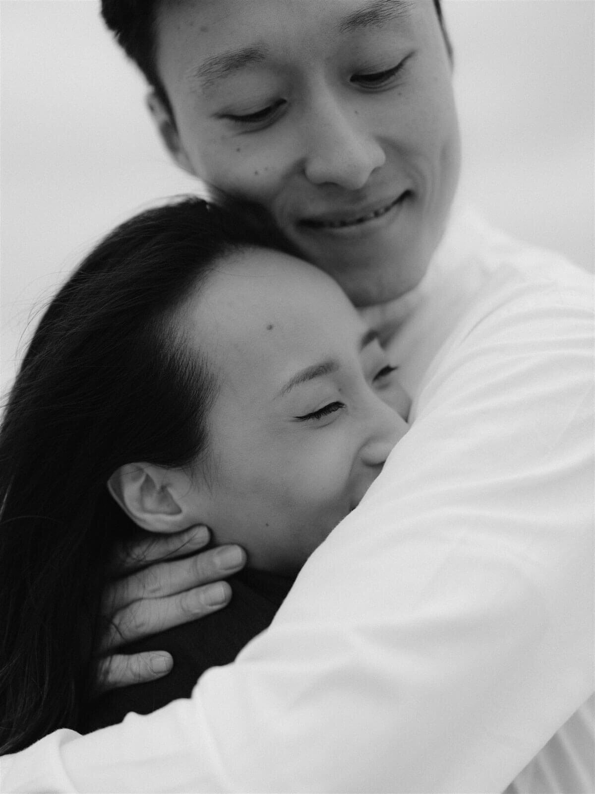 The engaged couple is lovingly hugging each other tightly in Fire Island Beach, NY. Engagement Image by Jenny Fu Studio