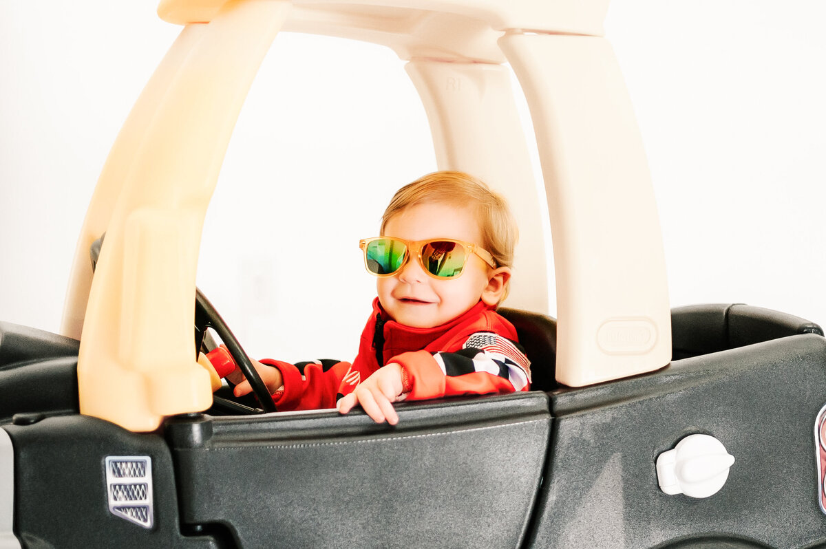 kids photography during 1st birthday milestone photography session of Close up of baby boy laughing in kids car