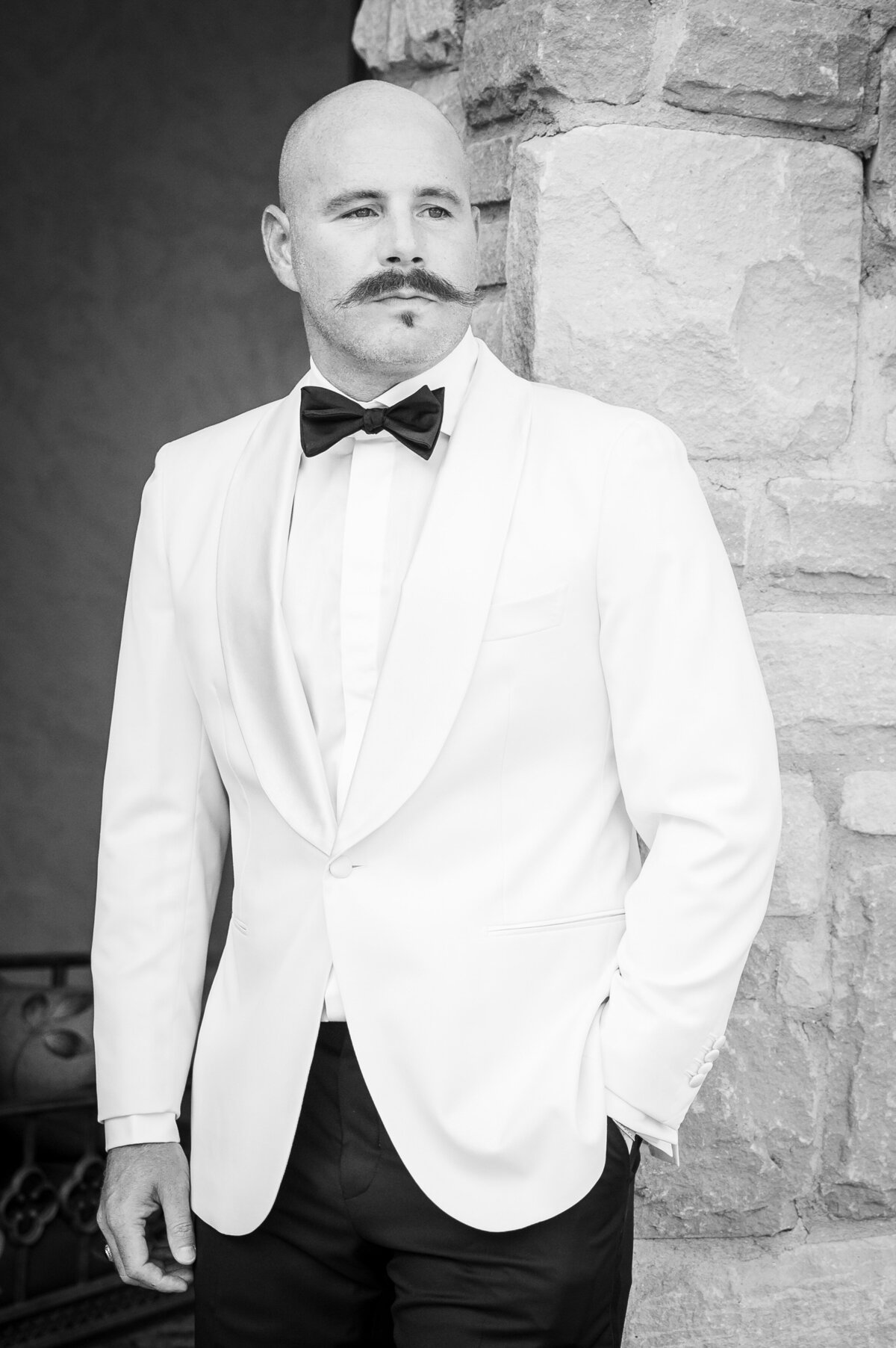 A groom stares off camera with a stoic look on his face.