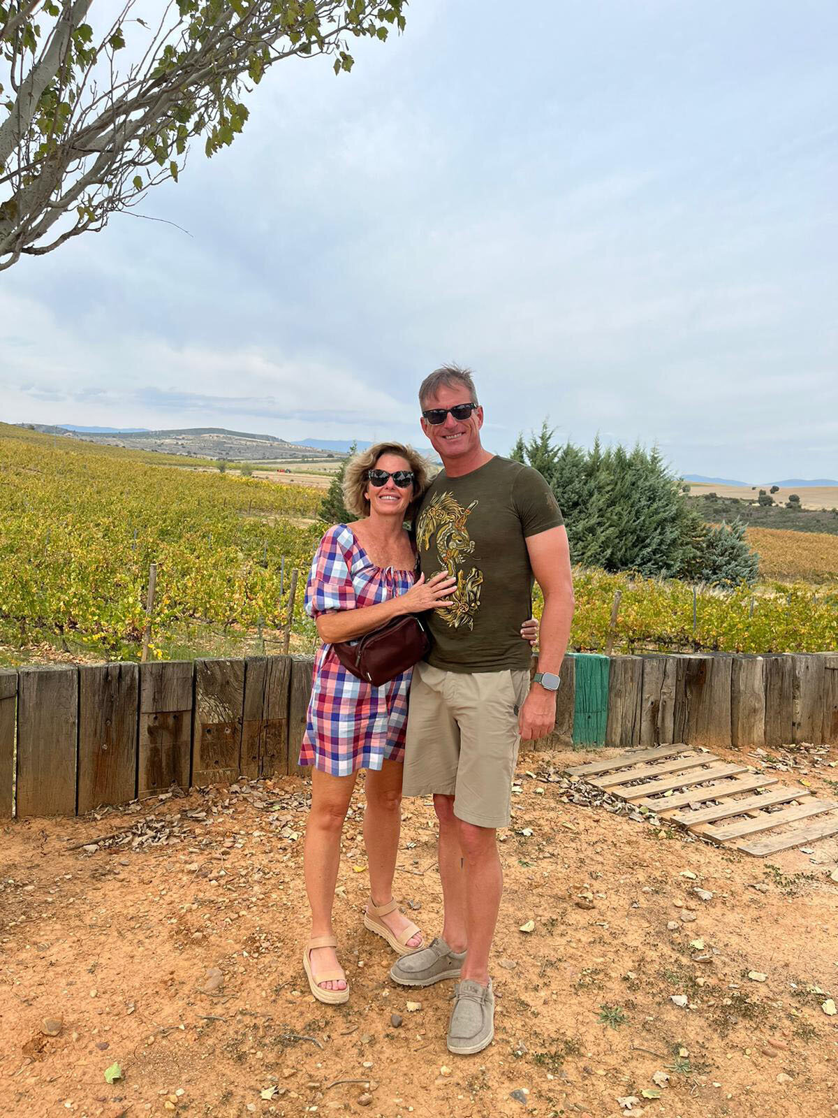 A couple posing for a photo with the scenic landscape of the winery in the background at the WGM Winery Lunch Experience.