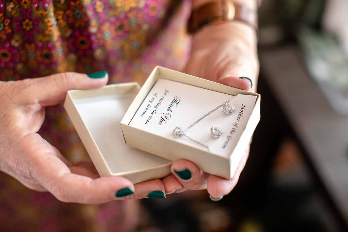 mother of the bride opens gift of necklace and earrings at Austin wedding
