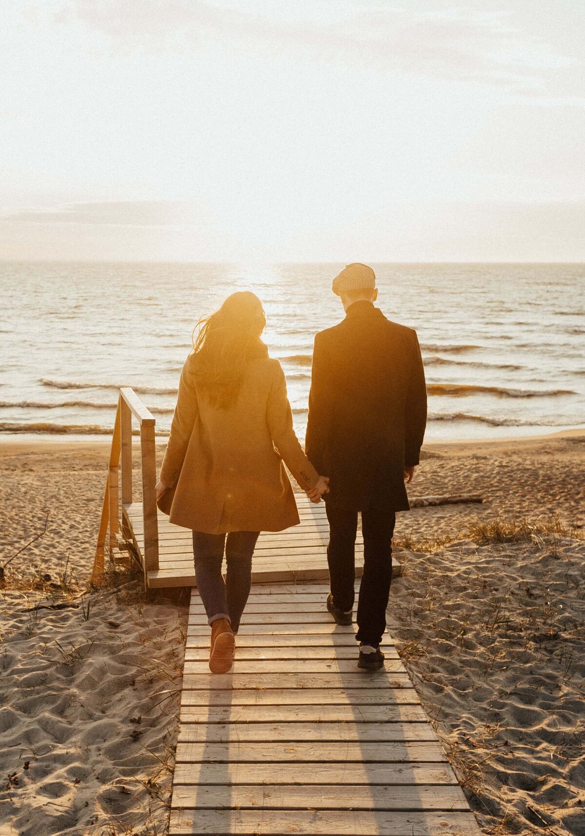 A Couple Walking on a Beach while Holding Hands