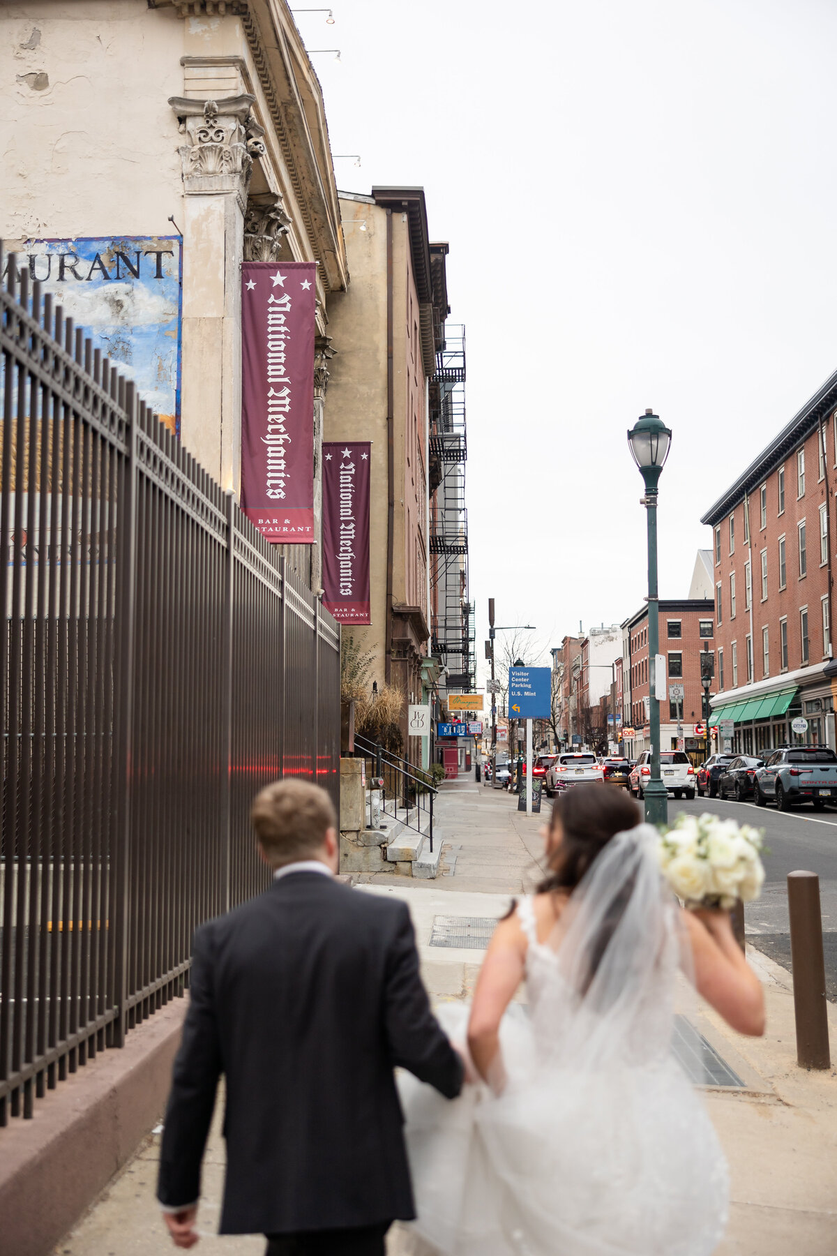 bride and groom holding hands walking in downtown philly to the national mechanic restaurant wedding photography by good omen photo co