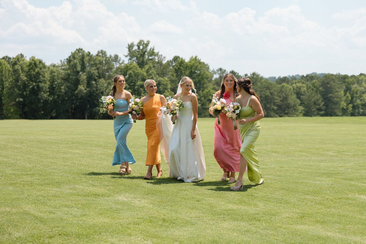 Bride and bridesmaids laugh as they walk arm in arm