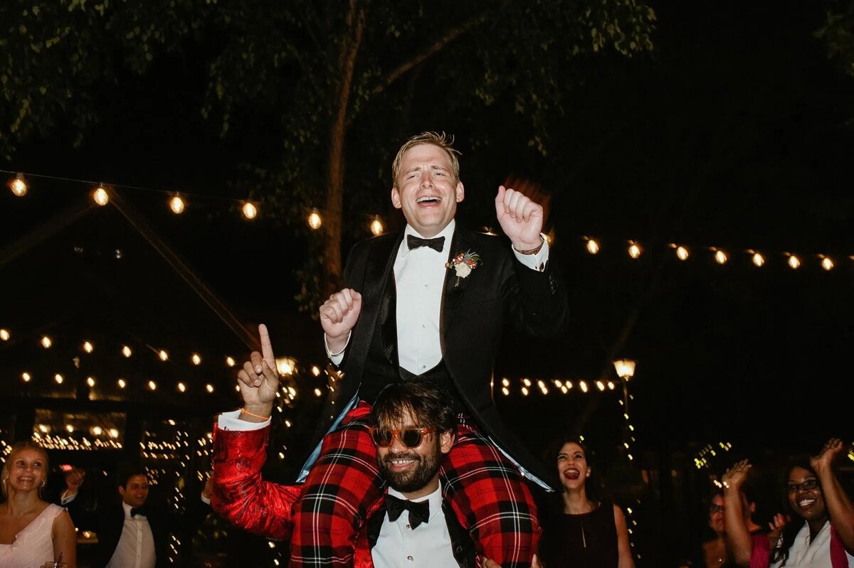 A groom on top of someone's shoulders.