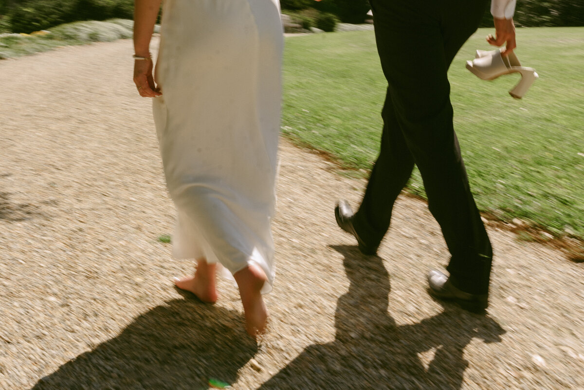 a motion blur photo of a wedding couple walking on a gravel road.