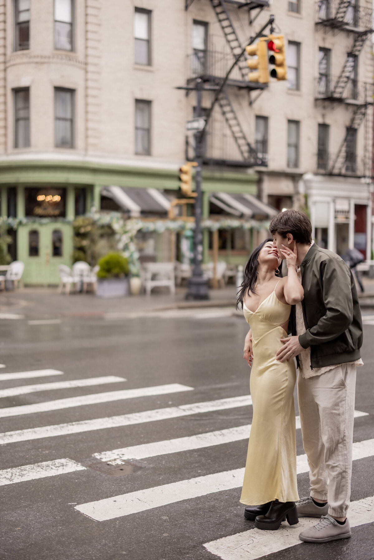 Couple kissing in the West Village at a crosswalk in front of Dante NYC, captured during a rainy day engagement session by Michelle Jackson Studio.