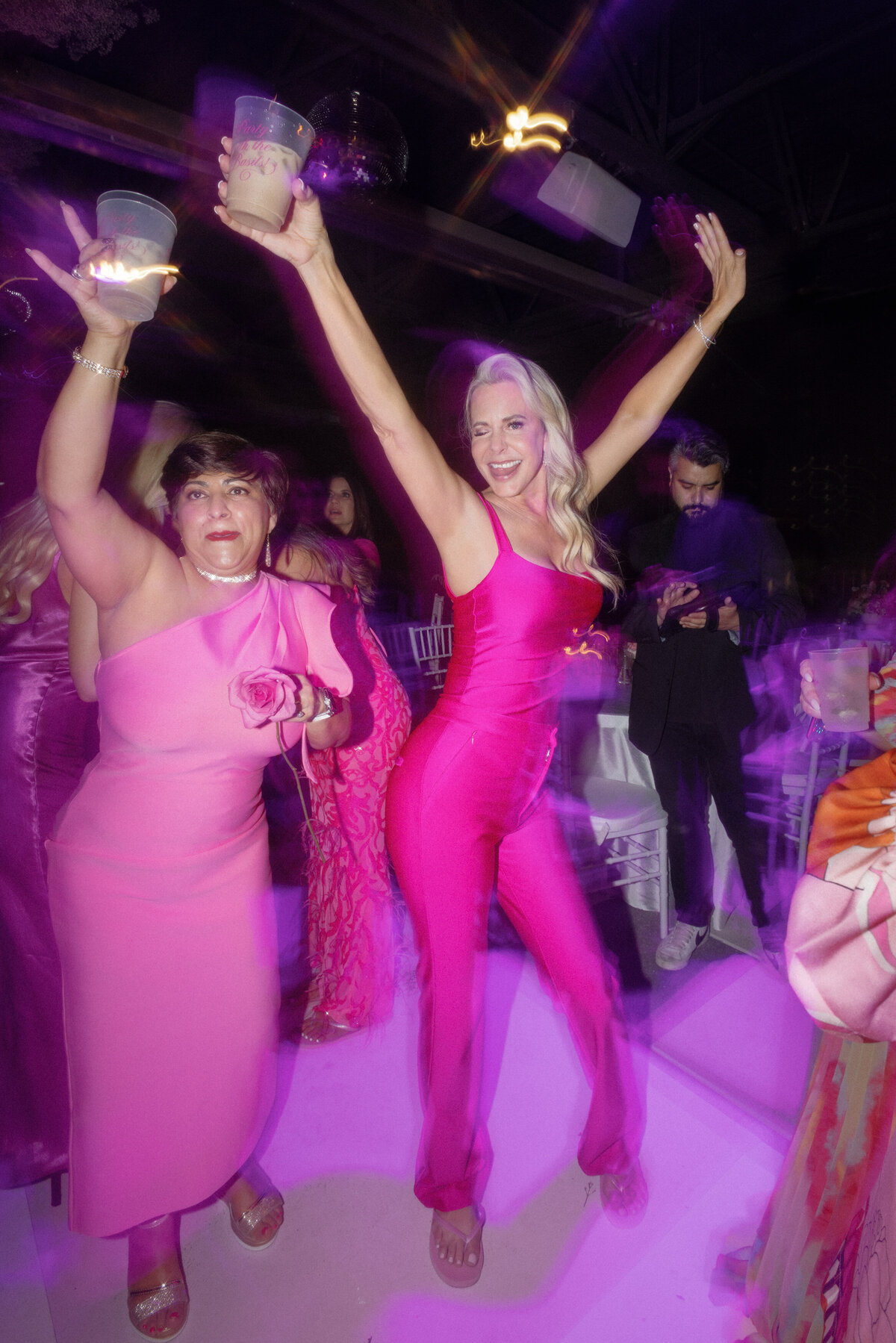 wedding guests wearing pink dancing at reception