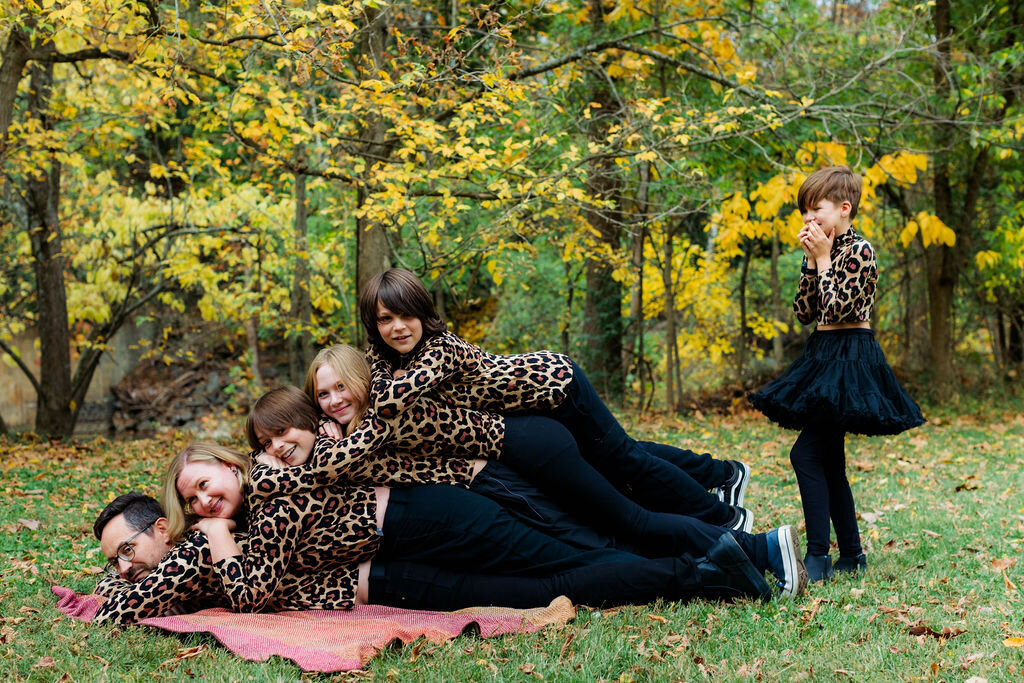 A family stacks on top of each other with matching leopard print shirts.