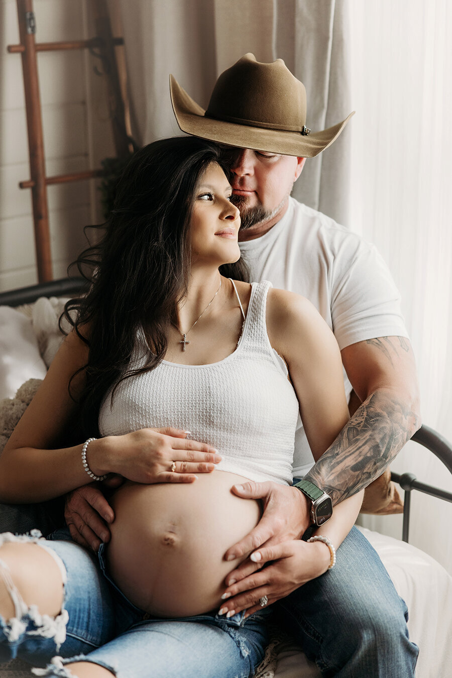 Pregnant mom sitting in dads lap snuggling in Fort Collins photo studio