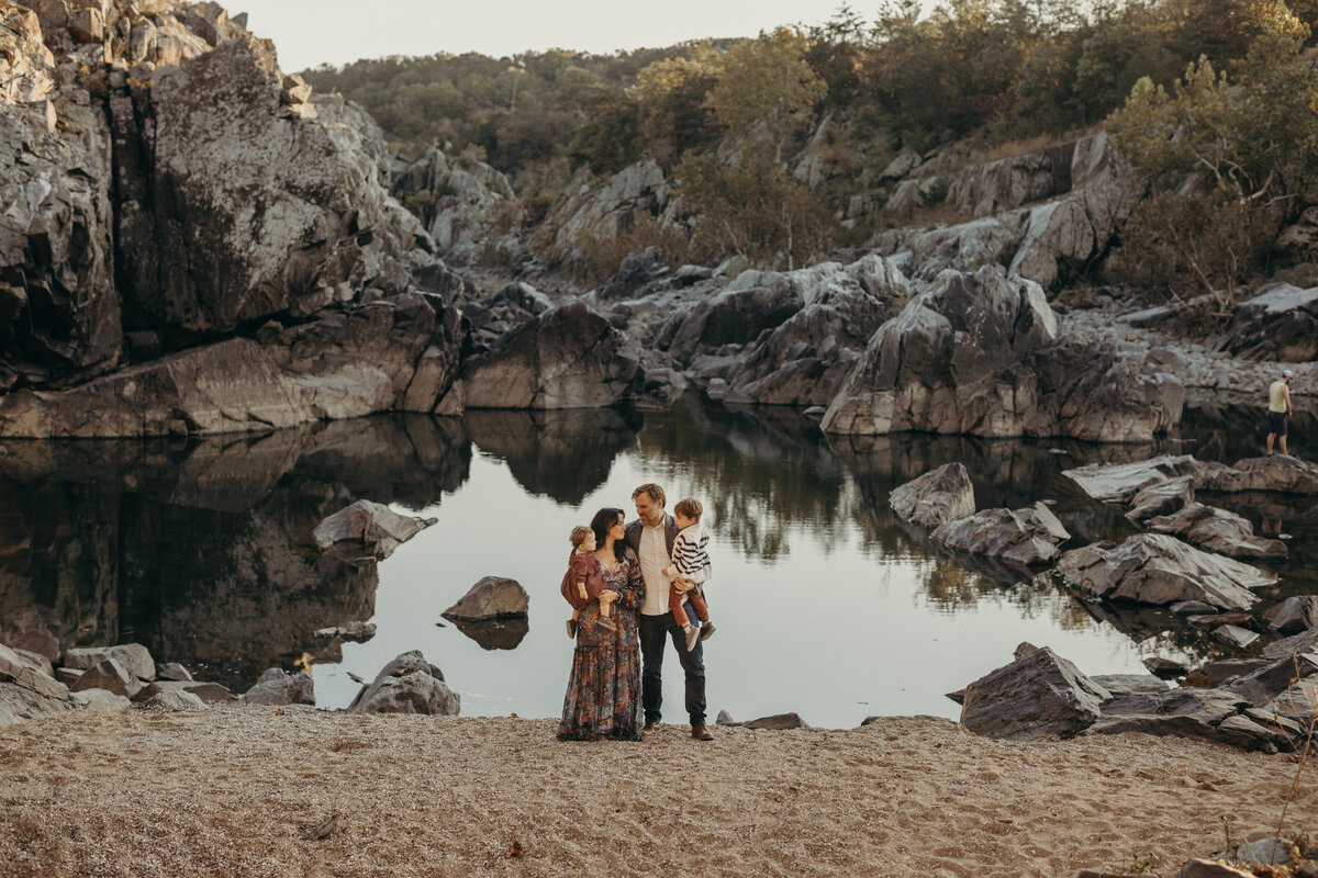 family standing against the lake at sunset
