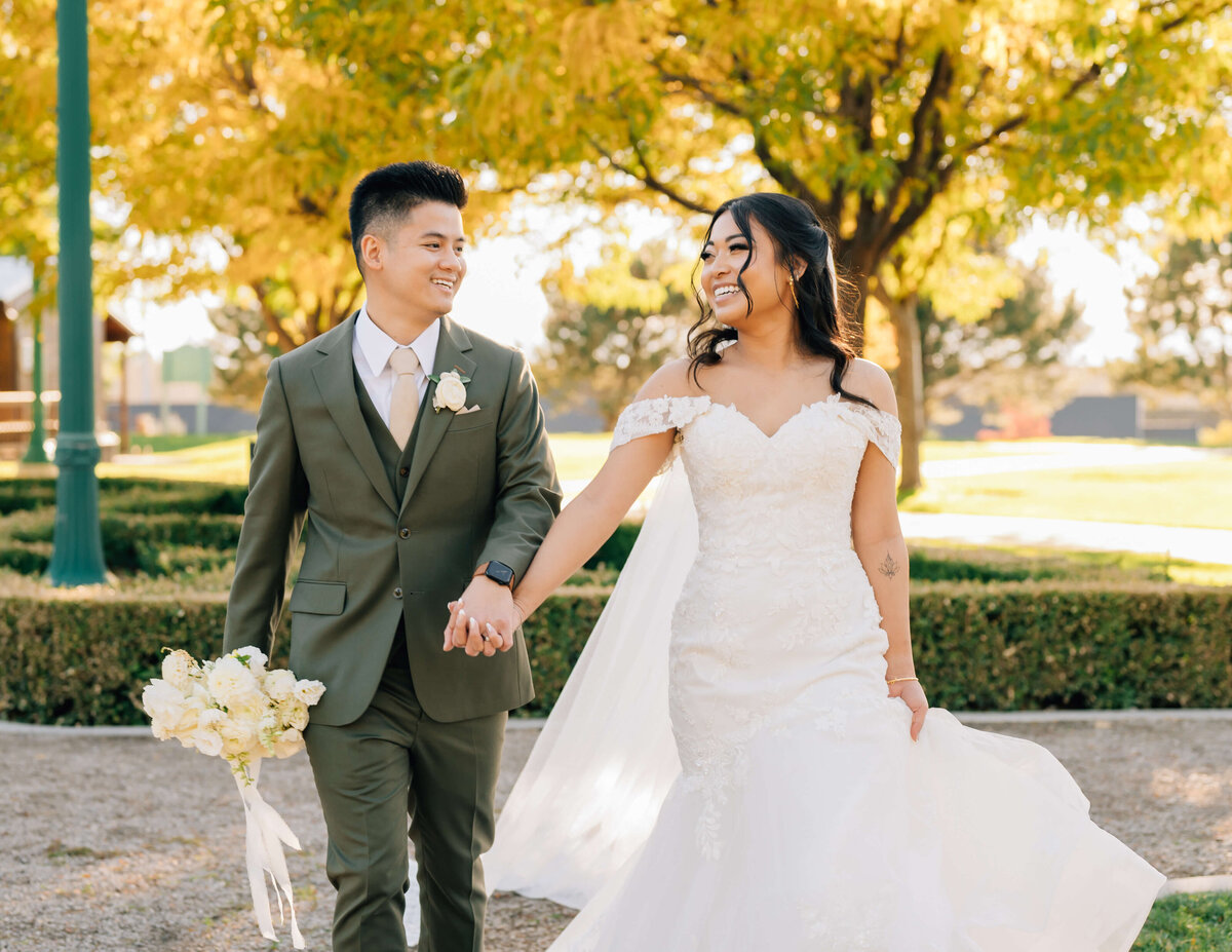 bride and groom holding hands while walking outside