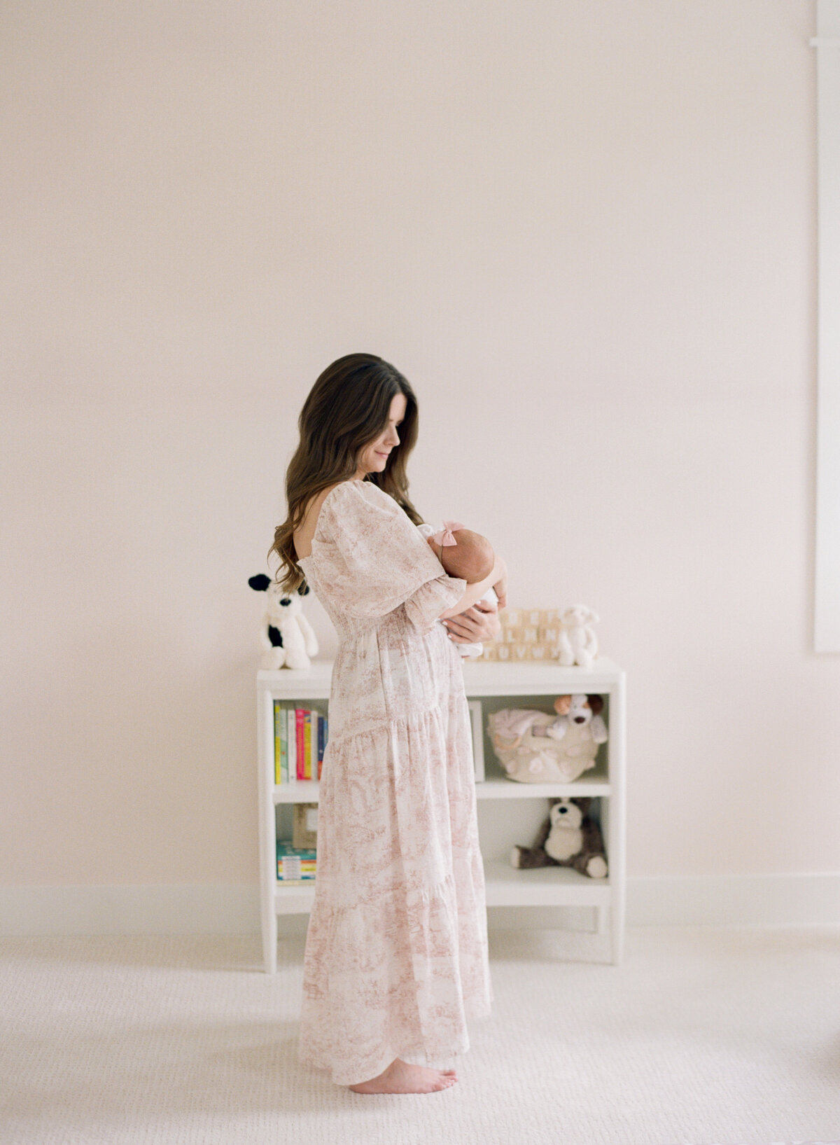 Mom stands in a beautiful neutral nursery during an Apex NC newborn photography session. Photographed by Raleigh Newborn Photographer A.J. Dunlap Photography.