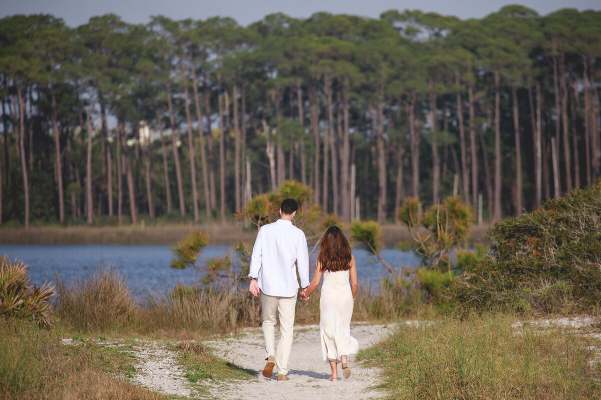 newly engaged couple walking holding hands on trail at grayton state park, florida.
