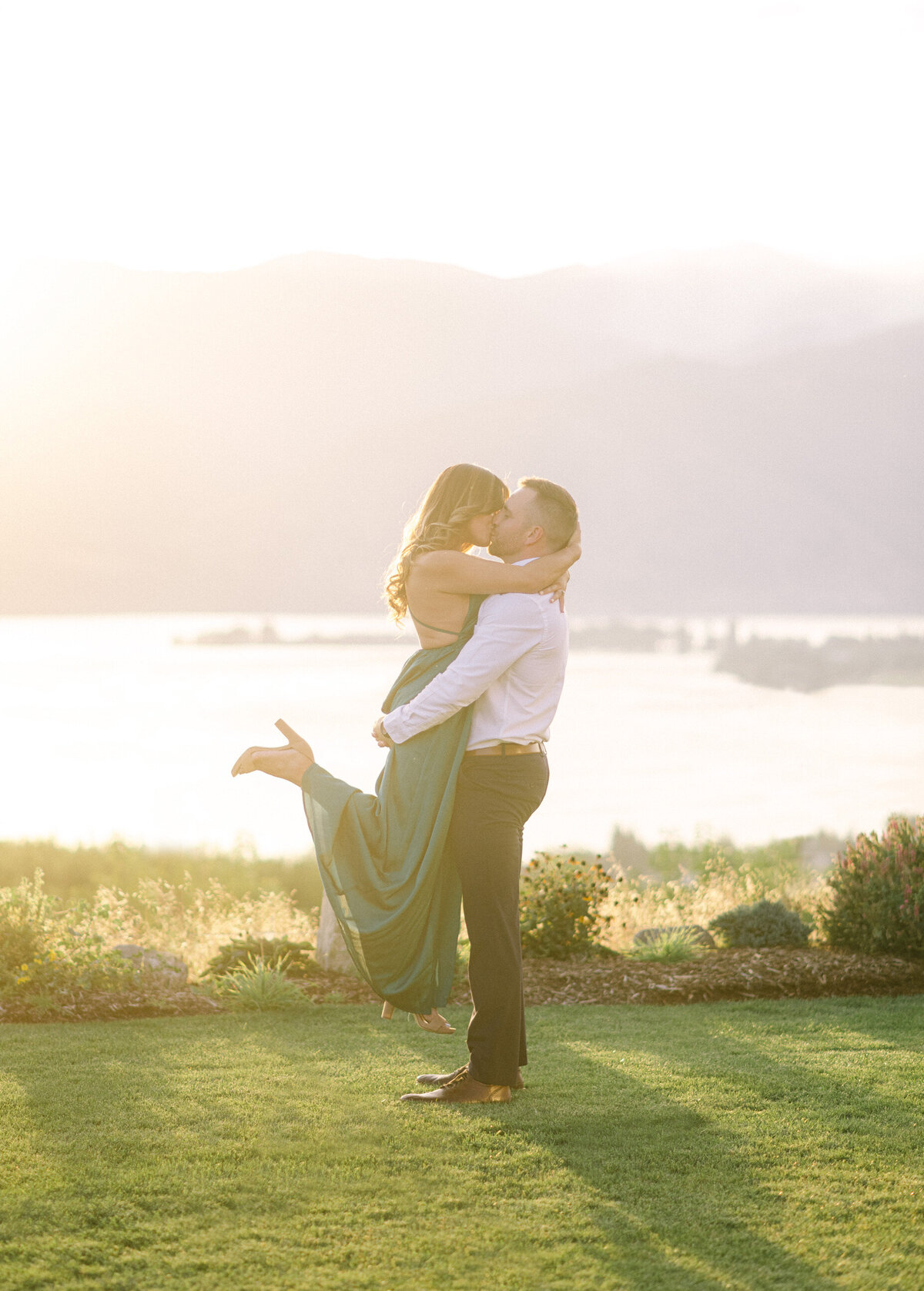 Engaged couple kissing in front of Lake Chelan sunset