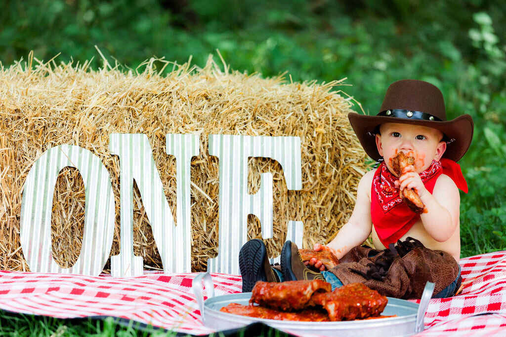 A child eats food with a cowboy hat next to a sign that says "ONE."