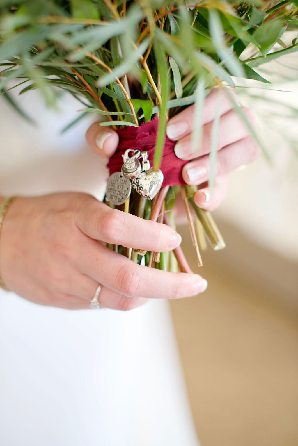 Hands holding the bottom of a wedding bouquet.