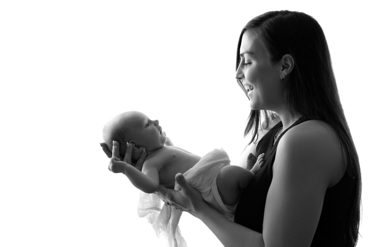 Black white mother lifting newborn baby Cedar Park lifestyle photographer