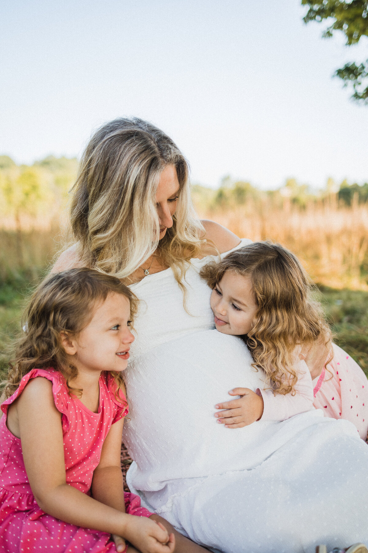 Mother with two daughters in a field during a maternity session in Cleveland, OH
